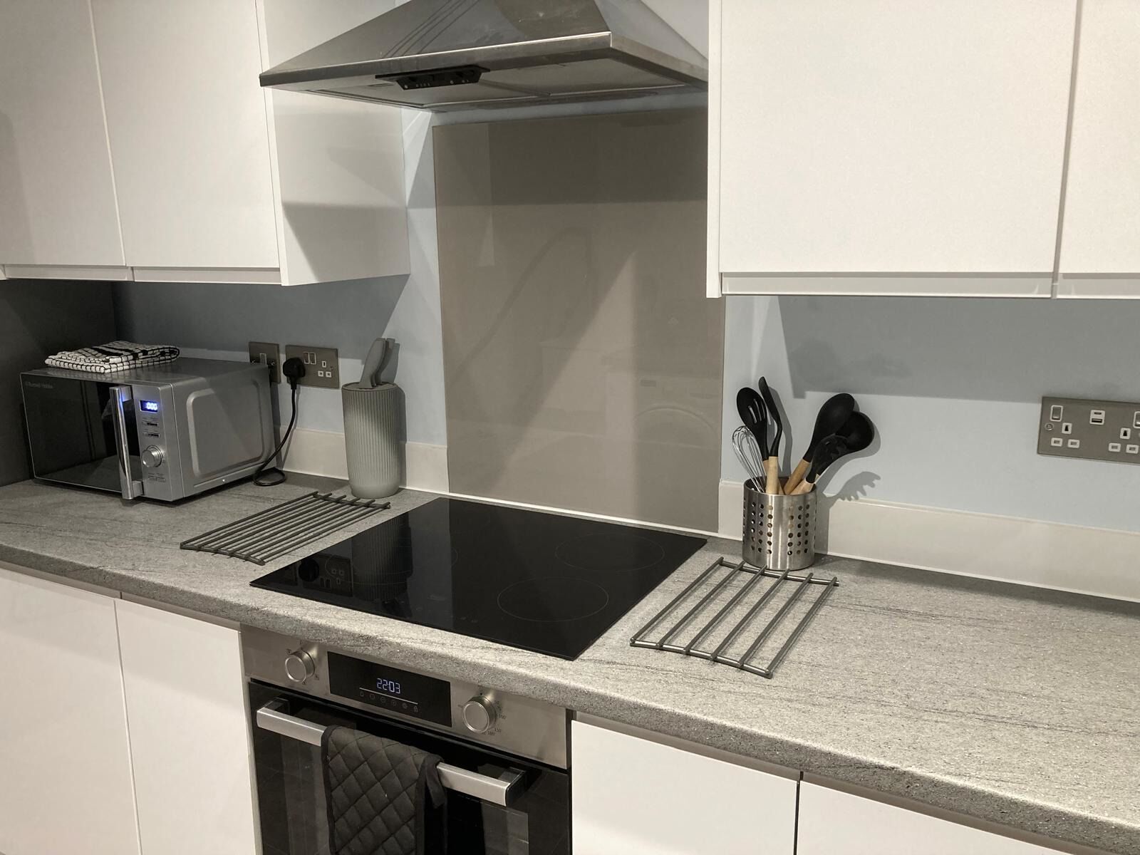 A kitchen with a built-in microwave, toaster, and a stainless steel range hood.