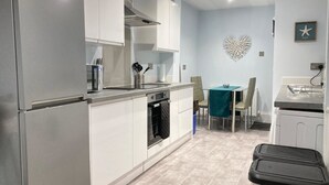 Una cucina moderna con forno integrato, un'area pranzo con tavolo e sedie, e un elemento decorativo a parete.