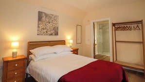 A bedroom with a bed, bedside tables, a red lamp, a shower, and a wardrobe. - Laundry Cottage (Strathpeffer)