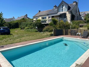 A rectangular swimming pool with a clear blue water surface, surrounded by a brick deck.