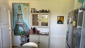 A kitchen with a white cabinet, a refrigerator, and a door with a mural of the Eiffel Tower.