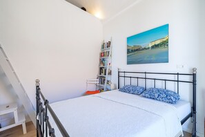 Ein Schlafzimmer mit Bett, Bücherregal, Gemälde und einer Treppe.