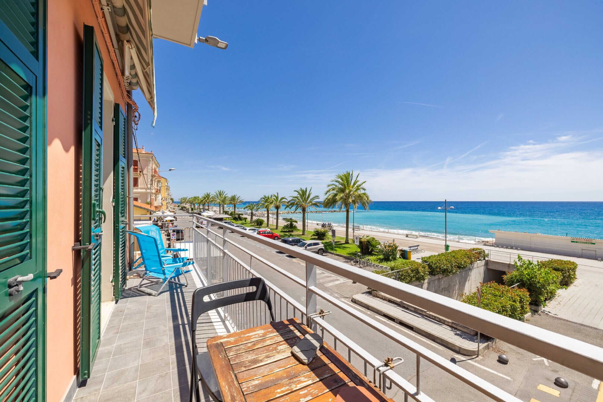 Ein Balkon mit Blick auf den Strand, eine Straße mit Autos und Palmen.