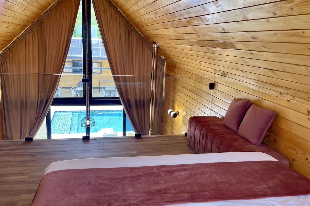 Un dormitorio con una cama grande, paredes de madera y vista a una piscina.