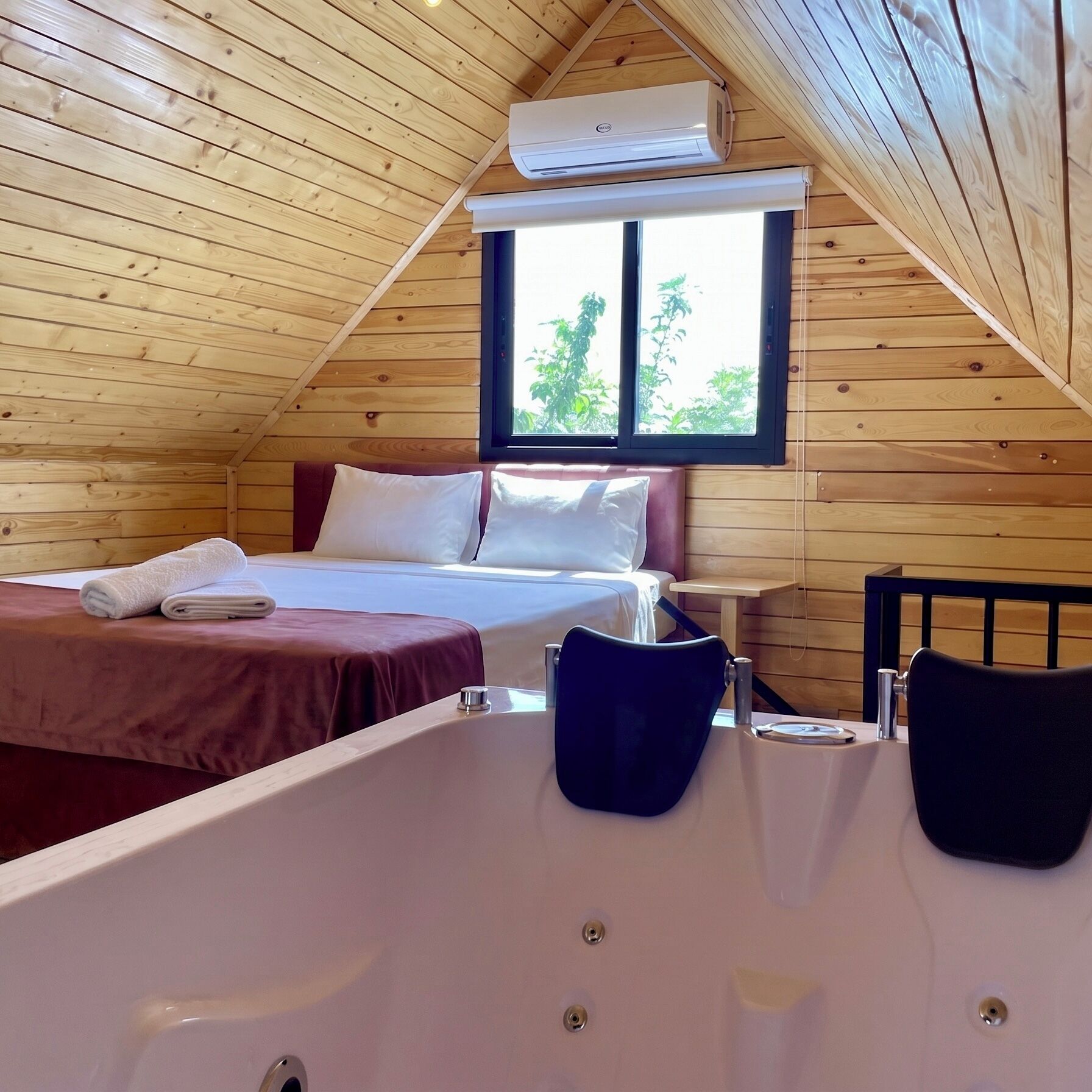 A bedroom with a bed, a window, and a bathtub.