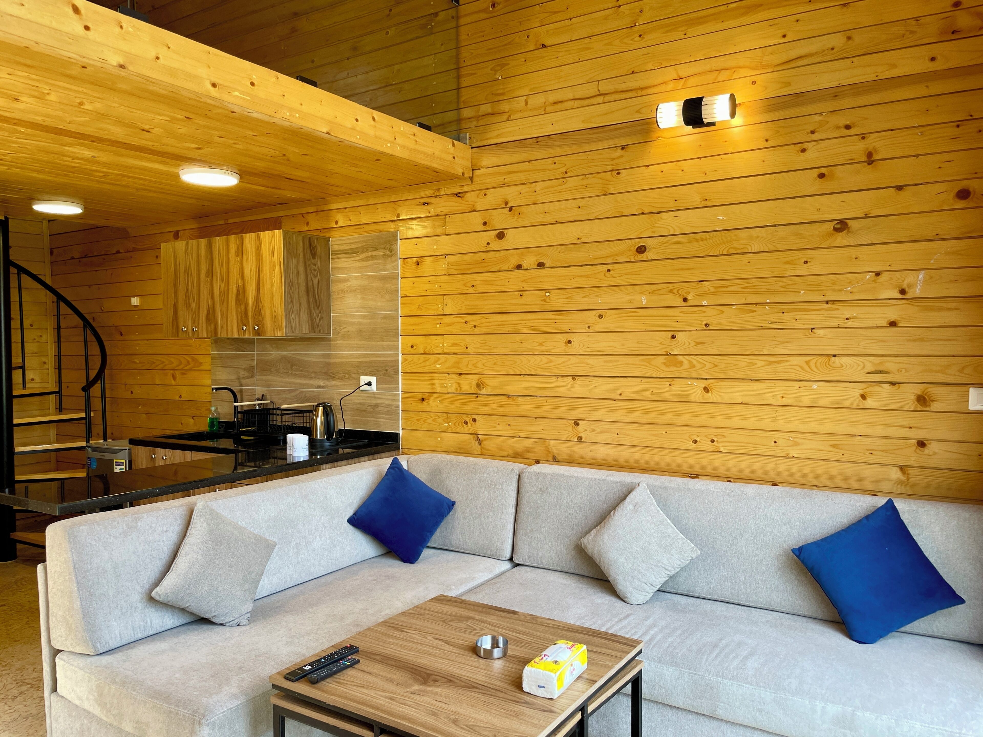 Un interior moderno de cabaña de troncos con sofá, mesa de centro y zona de cocina.