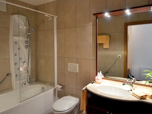 Une salle de bain avec une douche à parois de verre, des toilettes et un lavabo avec un miroir.