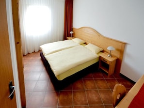 Une chambre d’hôtel avec un lit double, une table de chevet avec une lampe et une tête de lit en bois.