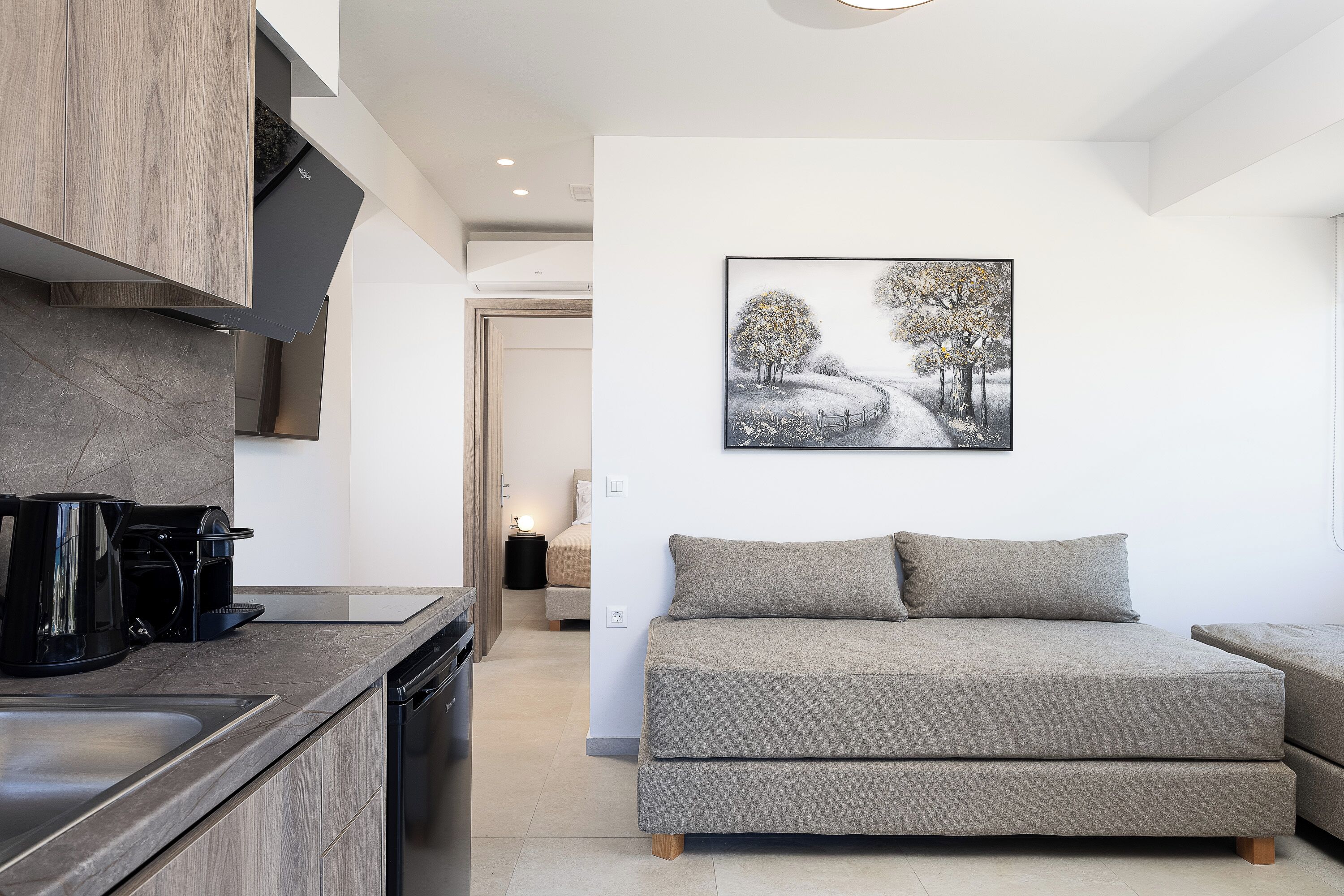 A modern kitchen with a coffee maker, a sofa, and a painting of a snowy landscape.