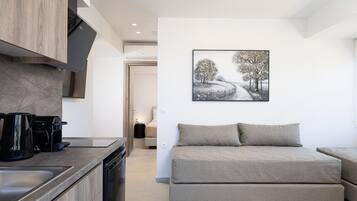 A modern kitchen with a coffee maker, a sofa, and a painting of a snowy landscape.