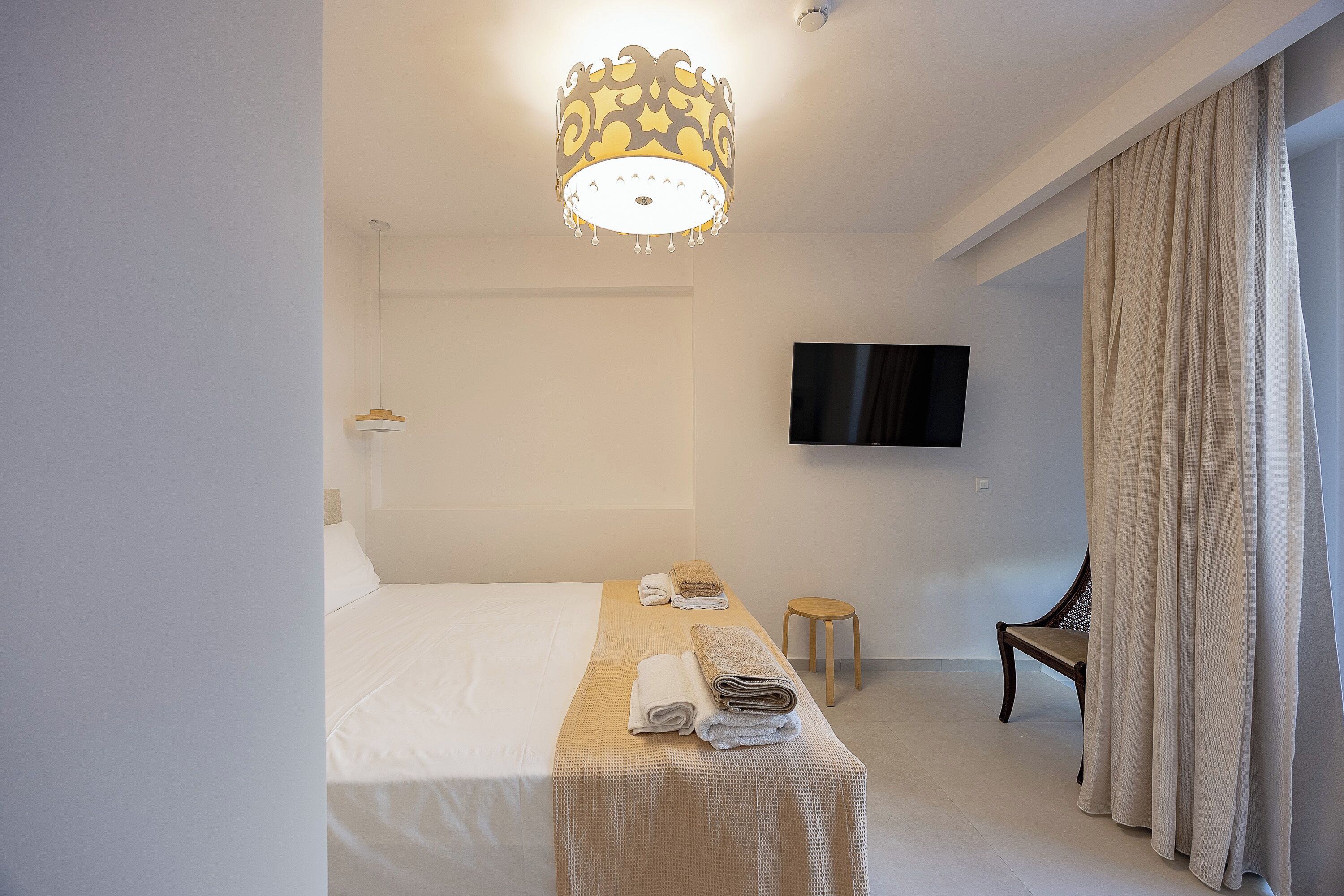 A hotel room with a bed, a television, a chair, and a table with towels.
