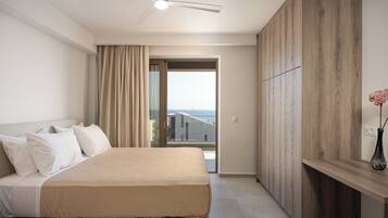 Habitación de hotel con cama, ventilador de techo, vista por una puerta de vidrio y un armario de madera.