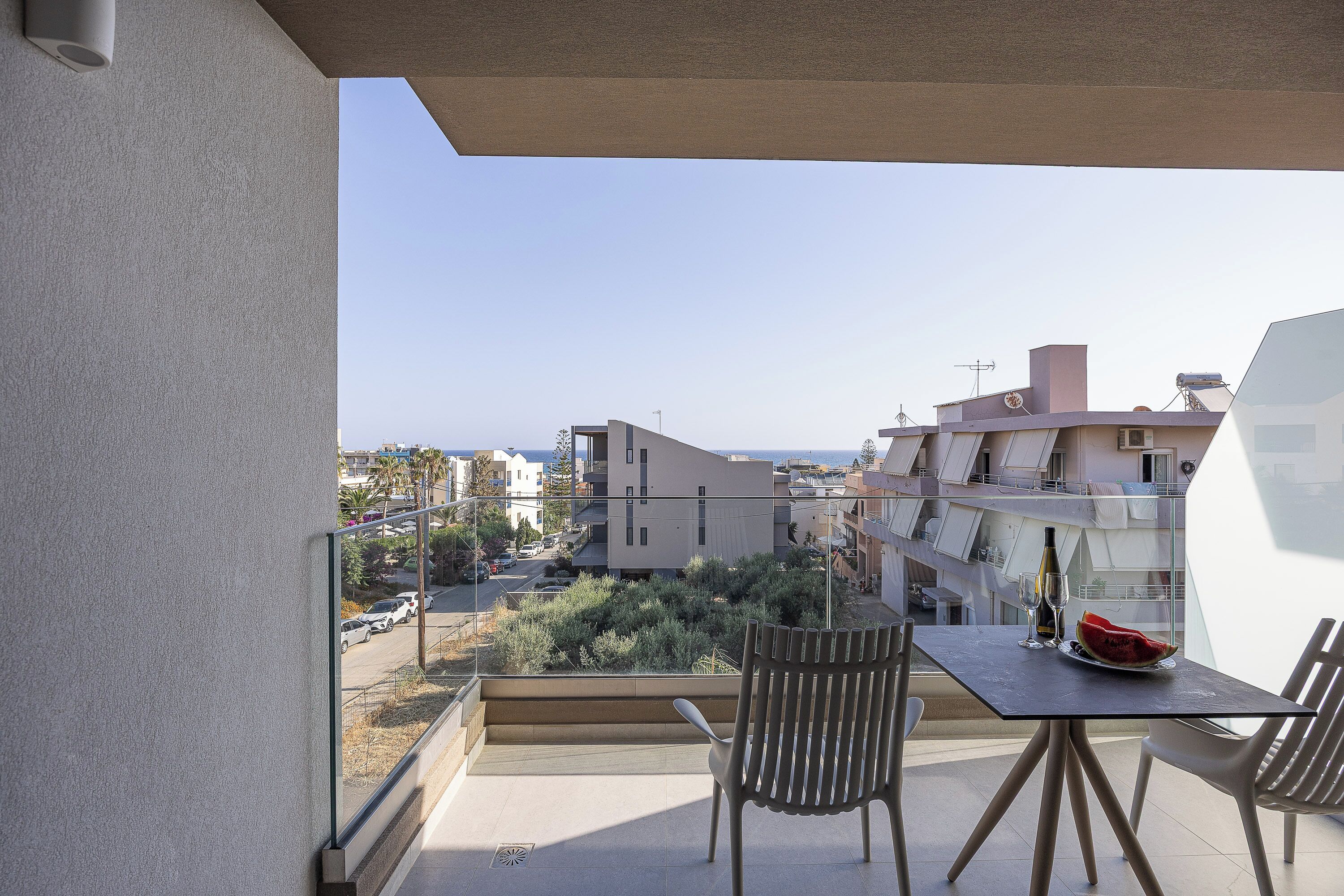 A balcony with a table, chairs, a bottle, and a glass.