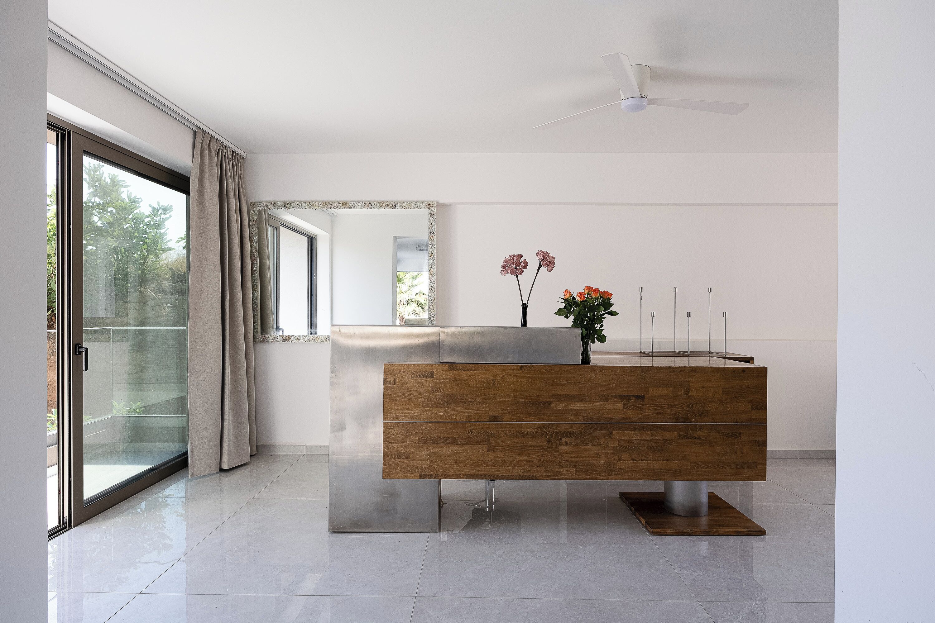Een moderne badkamer met een houten wastafelmeubel, een douchecabine met glazen wanden en een plafondventilator.