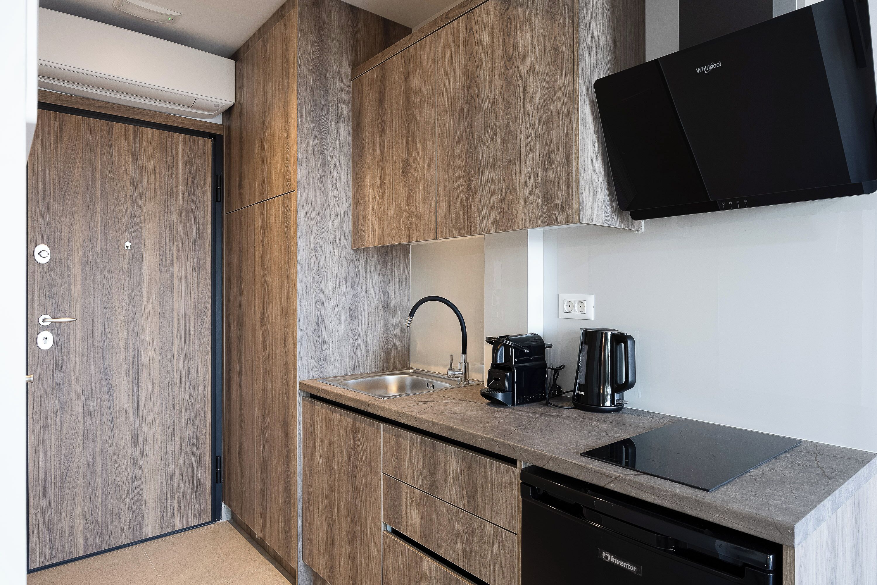 A modern kitchen with wooden cabinets, a black dishwasher, a coffee maker, and a built-in induction cooktop.