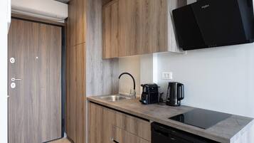 A modern kitchen with wooden cabinets, a black dishwasher, a coffee maker, and a built-in induction cooktop.