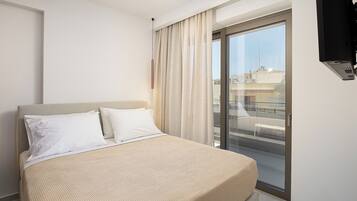 Habitación de hotel con cama, una ventana grande con cortinas, un televisor de pantalla plana y un balcón.