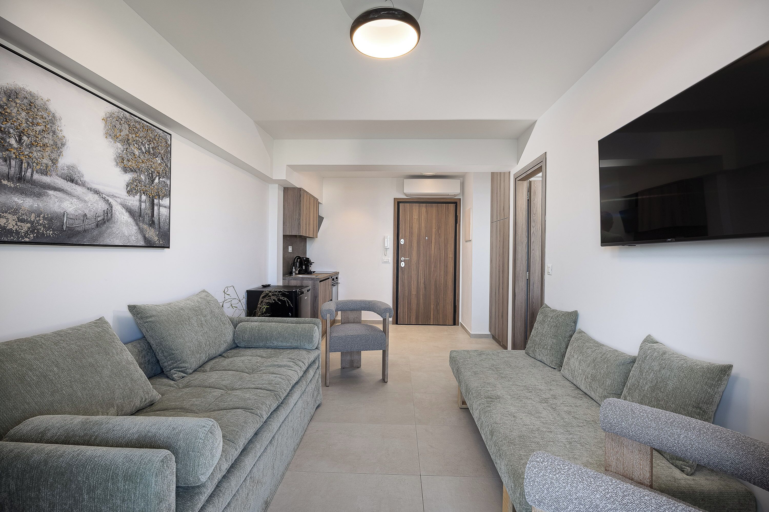 A modern living room with two sofas, a small table, and a TV mounted on the wall.