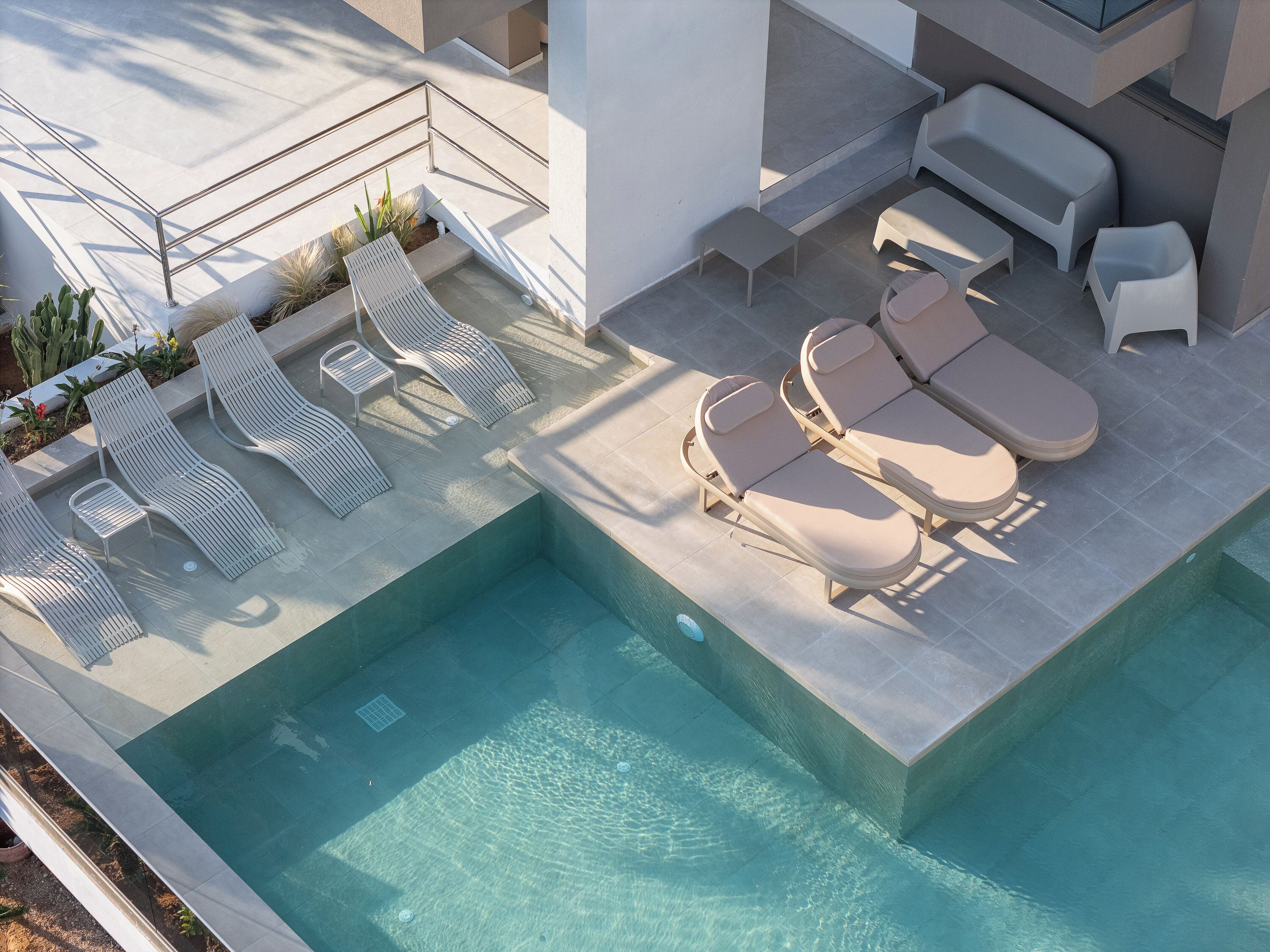 A rooftop pool area with sun loungers and a small table.