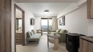 Una sala de estar moderna con un sofá, una mesa de centro, un televisor y vistas a través de un ventanal.