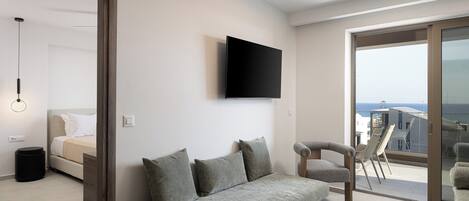 A modern living room with a sofa, a TV mounted on the wall, and a balcony with a view.