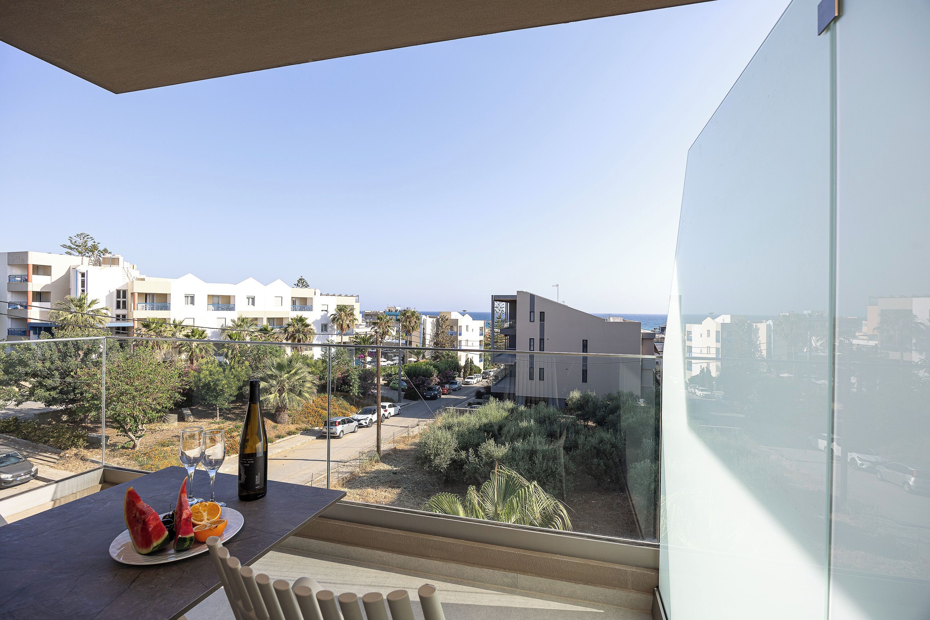 A balcony with a table, a bottle, glasses, and fruit.