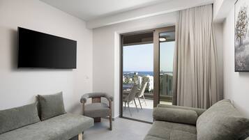 Un salon moderne doté d’un téléviseur à écran plat, de deux canapés, d’un fauteuil et d’un balcon offrant une vue agréable.