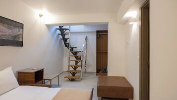 A bedroom with a bed, a bedside table, a wooden bench, a staircase, and a closet.