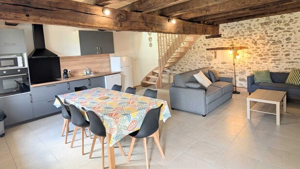 Una cocina moderna con comedor, una escalera y una sala de estar con sofá y lámpara.