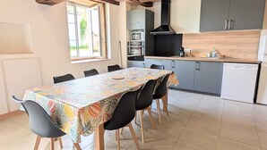 Un comedor con mesa, sillas y cocina al fondo.