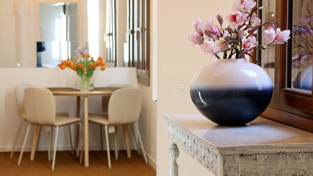 Ein Essbereich mit Tisch und Stühlen, einer Vase mit Blumen und einem dekorativen Spiegel.