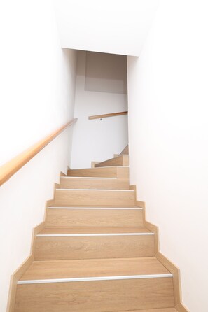 A wooden staircase with a handrail, leading to a landing with a wooden beam. - Venice 2 Green (Venezia)