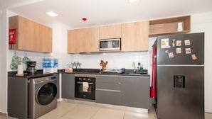 A modern kitchen with a washing machine, microwave, oven, and refrigerator. - Corporate Stays Centric Felix Bogado (Asunción)
