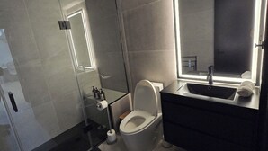 Ein modernes Badezimmer mit Toilette, Waschbecken und Spiegel.