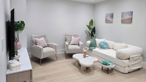Ein modernes Wohnzimmer mit einer Couch, zwei Sesseln, einem Couchtisch und einem Fernseher.