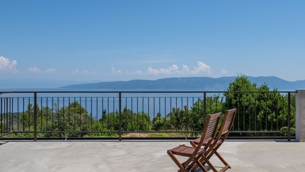 Un balcón con vista al mar y a las montañas.
