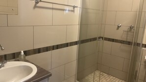 A bathroom with a shower, a sink, and a towel rack.