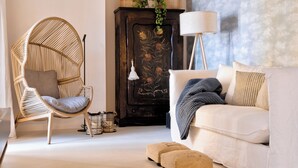 A room with a rattan chair, a sofa, a cabinet with floral carvings, and a floor lamp. - Apartment with a lake view in the center of Castelletto di Brenzone (Castelletto)
