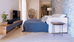 A modern bedroom with a bed, a TV on a shelf, a chair, and a small table. - Apartment with a lake view in the center of Castelletto di Brenzone (Castelletto)