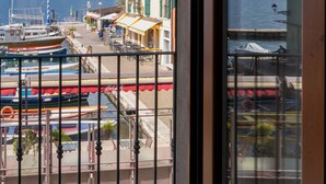 A view from a balcony overlooking a marina with boats, a mountain in the background, and buildings with balconies. - Apartment with a lake view in the center of Castelletto di Brenzone (Castelletto)