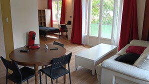 A room with a bed, a desk, a dining table with chairs, a sofa, and a window with curtains. - New, very comfortable 47 m² loft between Vercors and the foothills of the Chartreuse (Saint-Martin-le-Vinoux)