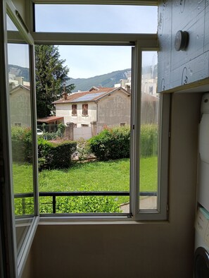 A window with a view of a residential area, including houses and greenery.