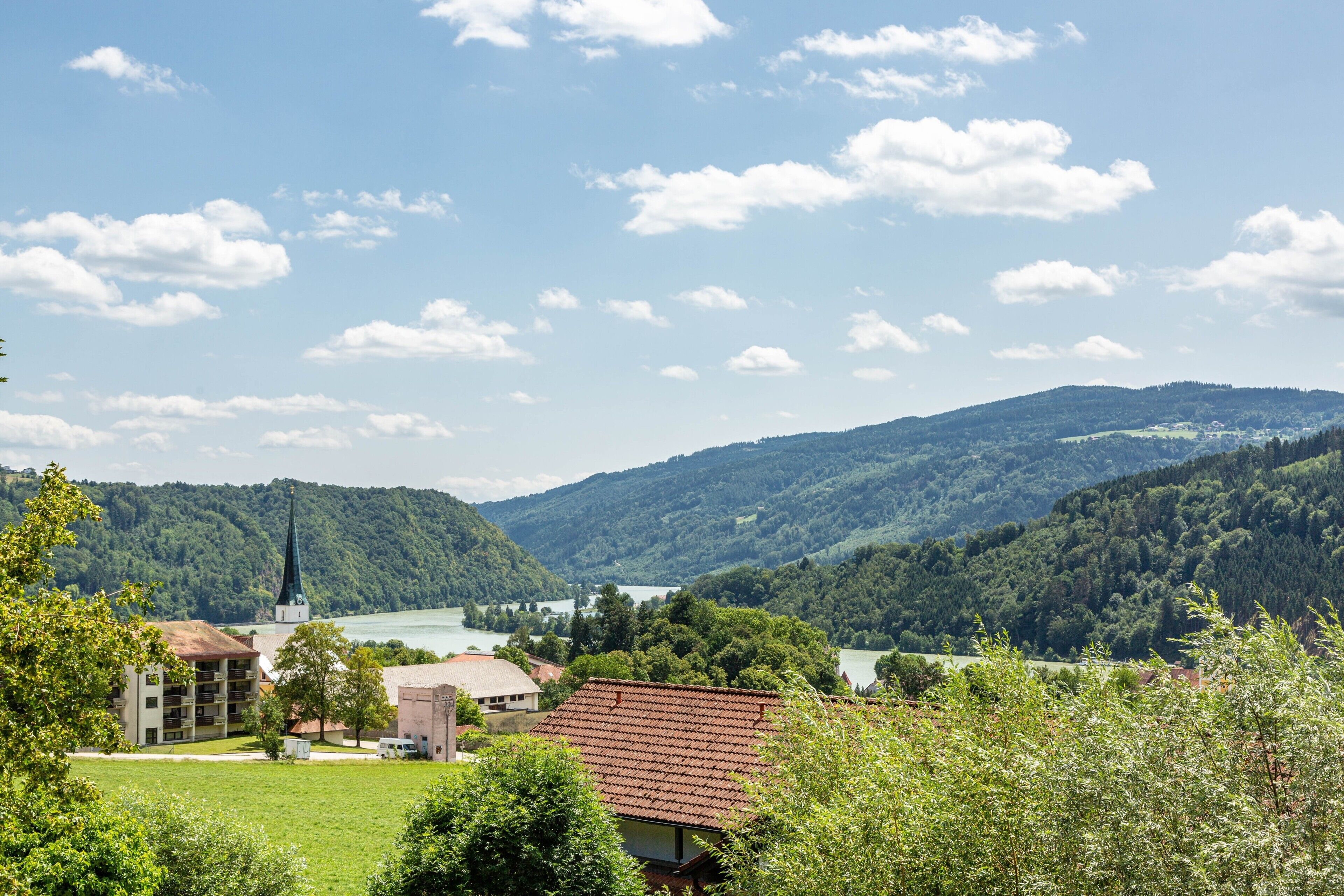 A rural landscape with a church, a lake, and hills in the background.