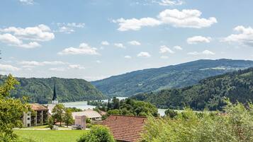 A rural landscape with a church, a lake, and hills in the background.
