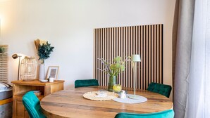 Et rundt træbord med grønt polstrede stole, en vævet plads og en vase med blomster.