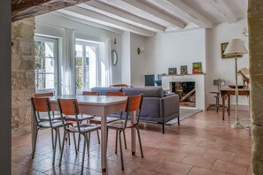 A spacious living area with a dining table, chairs, a sofa, and a fireplace. - Apartment with pool near Amboise | Sleeps 4 + 1 baby (Pocé-sur-Cisse)