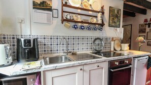A kitchen with a sink, stove, oven, and various appliances. There is a calendar and a shelf with dishes. - 4 Whiterow (Appin)