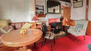 A cozy room with a wooden table, a chair, a sofa, a red carpet, a fireplace, and a mirror. - 4 Whiterow (Appin)