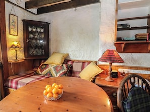 Ein gemütliches Zimmer mit einem Holztisch, einer Orangenschale, einer Couch mit kariertem Überwurf und einer Lampe.