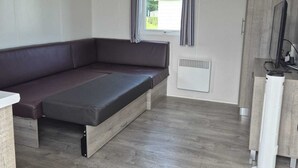 Una habitación con un banco incorporado, una ventana con cortinas, un radiador y un armario blanco.